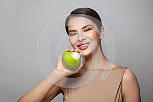 Attractive model woman biting green apple on white background