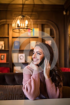 An attractive modern woman speaks on the phone with a client.