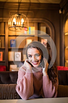 An attractive modern woman speaks on the phone with a client.