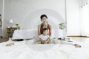 Attractive Mother Asian woman practice yoga with baby to meditation in bedroom after wake up in the morning