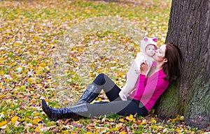 Attractive mother holding a baby girl playing with falling autumn leaves