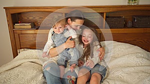 Attractive mother lying in bed with her pretty daughter and son. Handheld shot