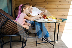 Attractive mother and sweet daughter making tea party on wooden porch