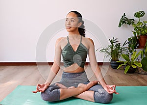 An attractive multi-ethnic woman sits cross-legged in Sukhasana yoga pose