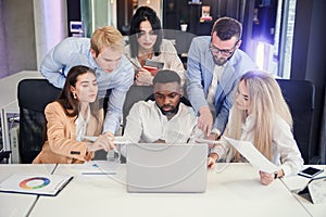 Attractive multiracial office managers discussing their business plan on the personal computer and analyse issues.