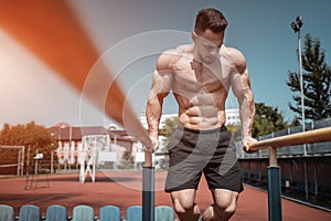 attractive muscular athlete man or bodybuilder pull up and exercising outdoor