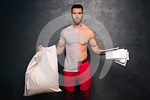 attractive muscular caucasian man holding a pillow and some papers, promoting a healthy lifestyle and fitness training