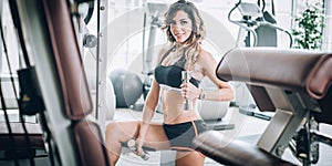 Attractive muscular fitness woman doing exercise with dumbbells in gym