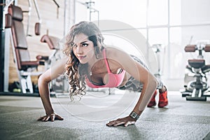 Attractive muscular fitness woman doing hard exercise in modern gym