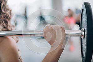 Attractive muscular fitness woman raising weight in the gym