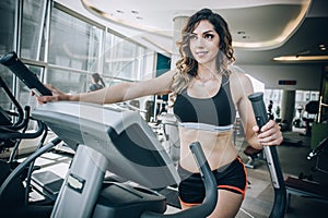 Attractive muscular fitness woman running on nordic ski in gym