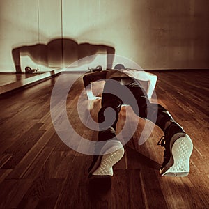 Attractive muscular man doing push-ups on a wooden floor. Toned image.