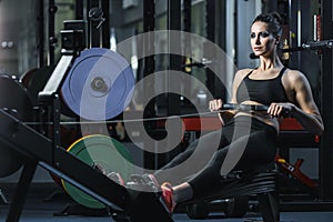 Attractive muscular woman CrossFit trainer do workout on indoor rower