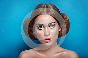 Attractive mysterious young woman with double hair bun in Princess Leia hairstyle looks towards the camera