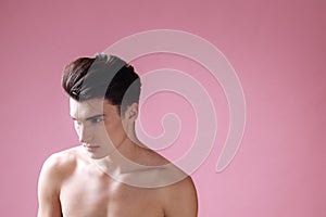 Attractive naked male standing over pink background