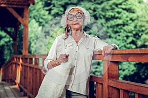 Attractive old lady posing on the wooden bridge outdoors