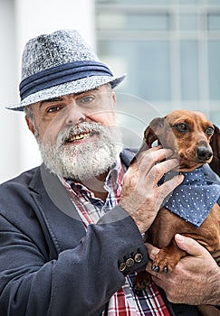 Attractive old man with beard and hat with dog teckel