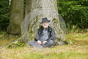 Attractive older man sitting under tree