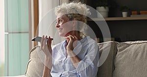 Attractive older woman holds smartphone talks on speakerphone