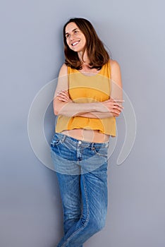 Attractive older woman smiling with arms crossed by gray wall