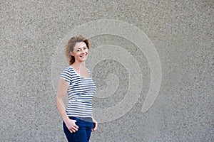 Attractive older woman with striped shirt smiling against wall