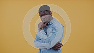 Attractive pensive confident african american man looking at camera wearing a denim shirt rubbing his chin.