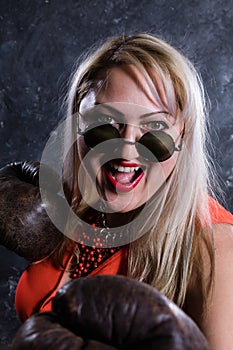 Attractive plump woman with boxing gloves and sunglasses studio portrait