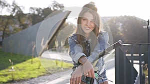 Attractive portrait of lovely happy young woman with long hair and jeans clothes on bicycle posing on camera on the