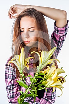 Attractive posing girl with straight long hair holds lily flowers