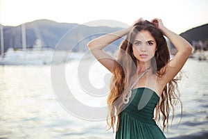 Attractive posing teen girl on the beach at sunset by the yacht