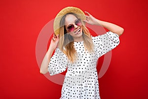 Attractive positive happy young blonde woman wearing everyday stylish clothes and modern sunglasses isolated on colorful