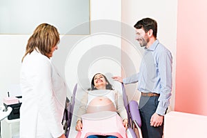 Attractive pregnant couple at the consulting room with a female doctor