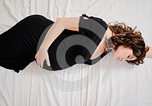 a attractive pregnant woman in a black dress in bed