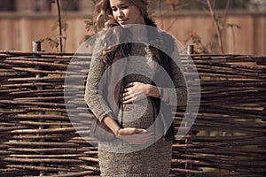 Attractive pregnant woman in cozy clothes at countryside