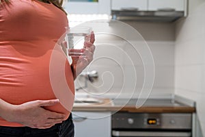 Attractive pregnant woman drinking water.