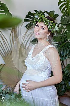 Attractive pregnant woman in green leaves wreath