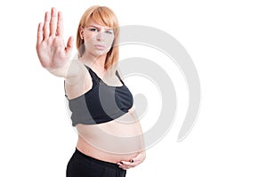 Attractive pregnant woman showing stop or stay gesture with palm