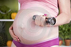 Attractive pregnant woman using a dumbbell while training
