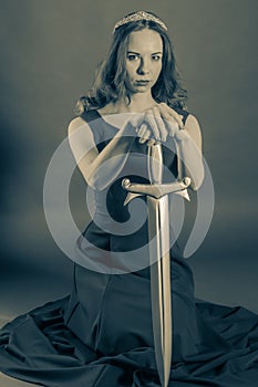 Attractive princess girl kneeling with a sword