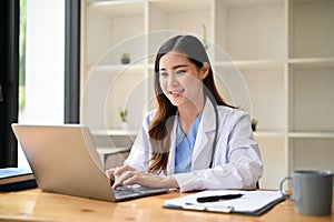 An Asian female doctor working on her medical research on laptop in her hospital office