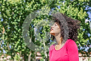 Attractive racial woman with afro hair breathes relaxed in a park
