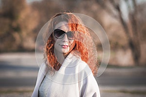 Attractive red-haired woman in sunglasses and a coat