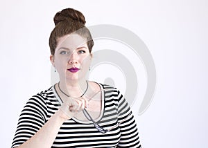 Attractive redhead removes her glasses and stares at the camera with confidence on a white background with room for text