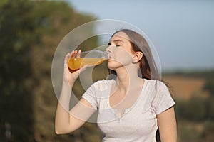 Young woman drinks orange juice on a sunny summer day photo