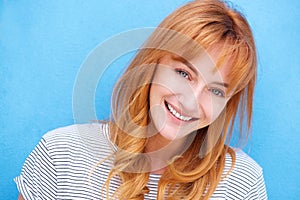 Attractive redhead woman laughing by blue wall