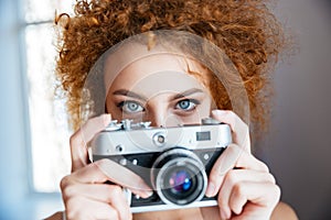 Attractive redhead woman photographer using old camera