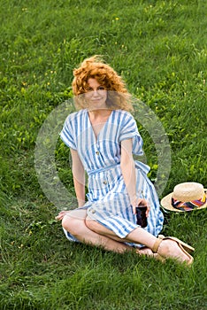 attractive redhead woman sitting on grass