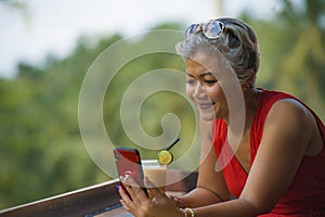 Attractive and relaxed Asian woman with grey hair and stylish red dress using social media on inernet mobile phone at beautiful