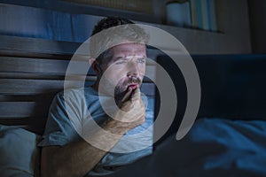 Attractive and relaxed internet addict man networking concentrated late at night on bed with laptop computer in social media