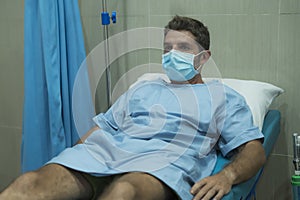 Attractive and scared man infected by covid-19 - dramatic portrait of adult male in face mask receiving treatment at hospital